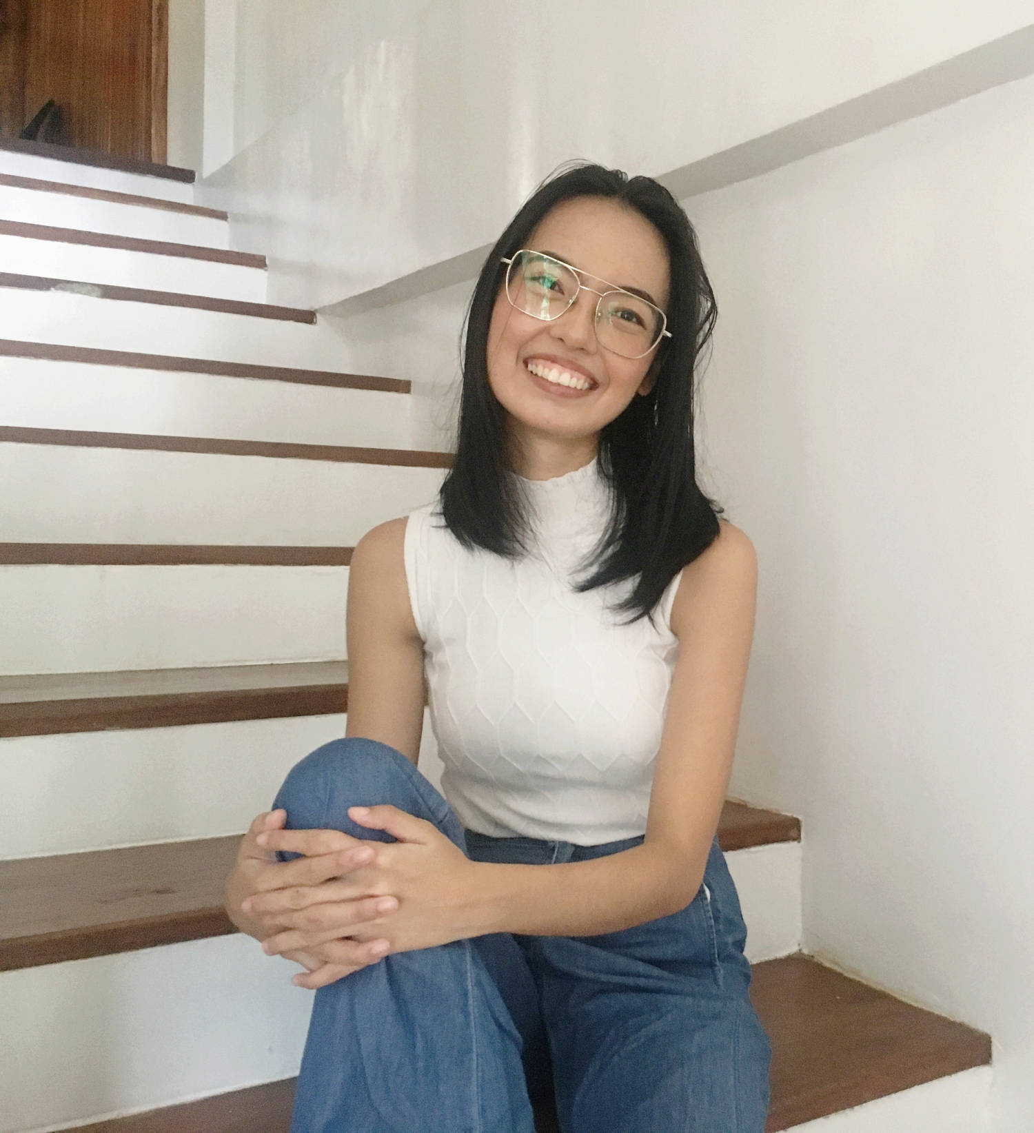 Ash wearing a white top smiling to the camera